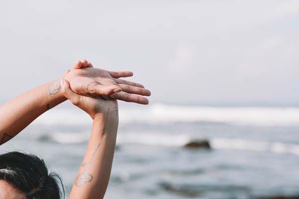 Woman with arms lifted during online somatic coaching