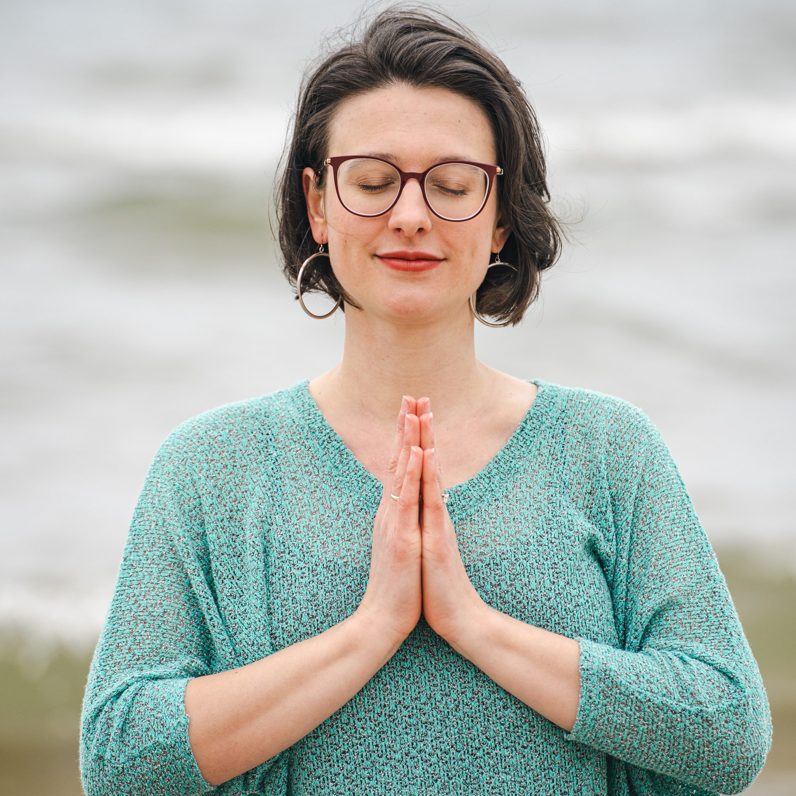 Carli Watson with hands in prayer pose during online somatic coaching